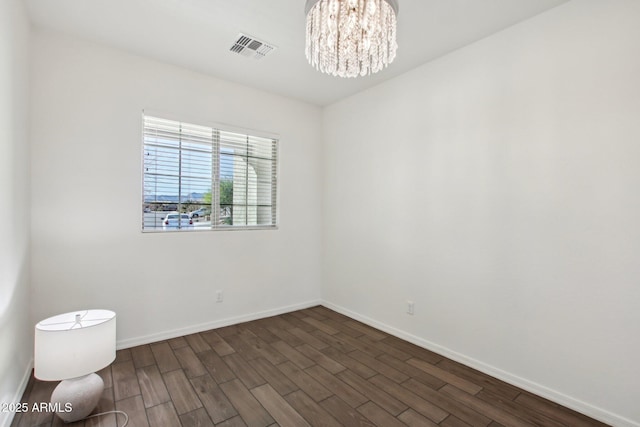 unfurnished room with dark hardwood / wood-style flooring and an inviting chandelier