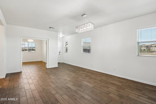 unfurnished room with an inviting chandelier and dark hardwood / wood-style flooring