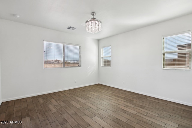 empty room featuring an inviting chandelier and dark hardwood / wood-style floors