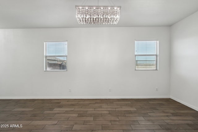 spare room featuring a healthy amount of sunlight and an inviting chandelier