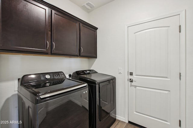 laundry area with washer and dryer, light hardwood / wood-style flooring, and cabinets