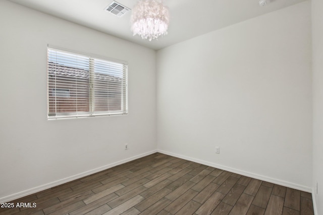 spare room featuring a notable chandelier and wood-type flooring