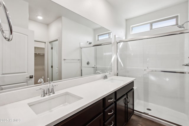 bathroom featuring a shower with shower door and vanity