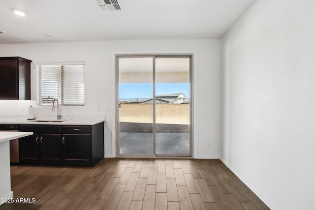 kitchen with a healthy amount of sunlight, dark brown cabinets, sink, and dark hardwood / wood-style floors