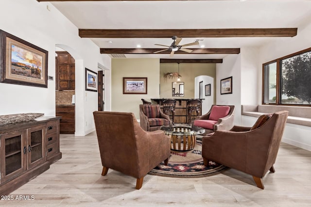 living room featuring beamed ceiling, light wood-type flooring, and ceiling fan