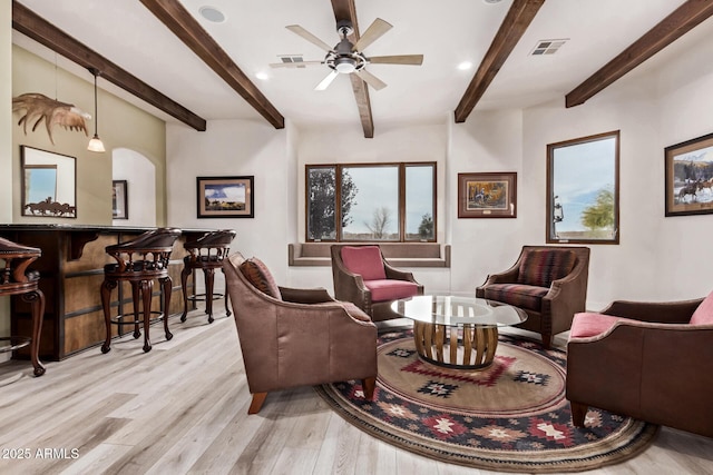 living room featuring ceiling fan, beam ceiling, indoor bar, and light hardwood / wood-style flooring