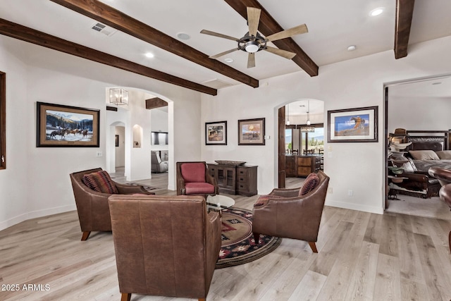 living room with beamed ceiling, ceiling fan with notable chandelier, and light hardwood / wood-style flooring