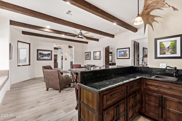 kitchen with beam ceiling, ceiling fan, sink, decorative light fixtures, and light wood-type flooring