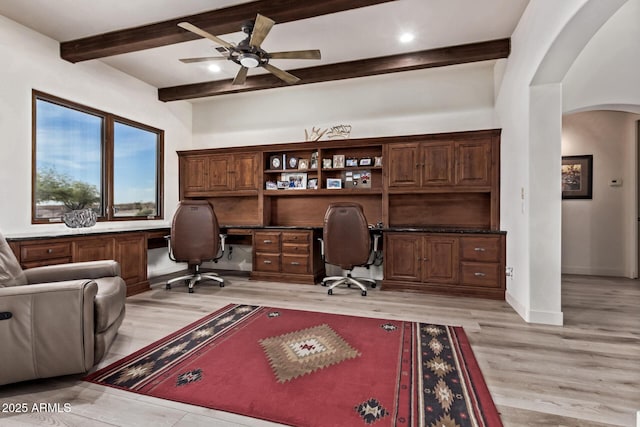 office with beam ceiling, ceiling fan, light hardwood / wood-style flooring, and built in desk