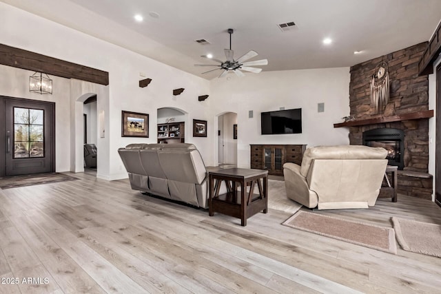 living room featuring a fireplace, vaulted ceiling, light hardwood / wood-style flooring, and ceiling fan with notable chandelier