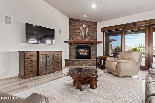 living room featuring a fireplace, light hardwood / wood-style floors, and vaulted ceiling