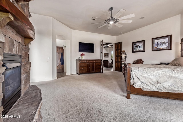 bedroom with ceiling fan, a fireplace, and light colored carpet