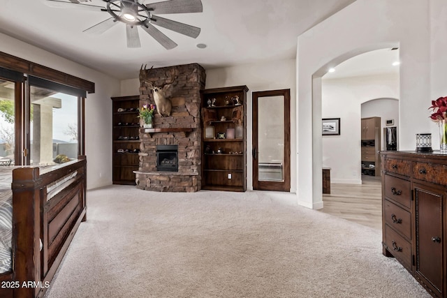 living room with a fireplace, light colored carpet, and ceiling fan