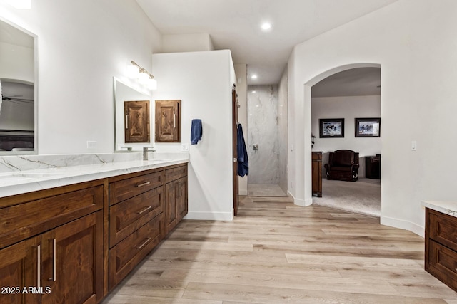 bathroom featuring hardwood / wood-style floors, vanity, ceiling fan, and walk in shower