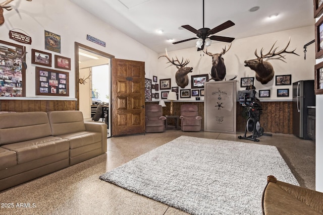 living room featuring ceiling fan and wooden walls