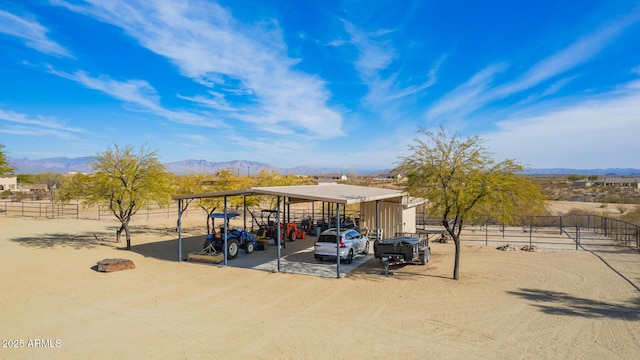 view of car parking with a carport, a mountain view, and a rural view