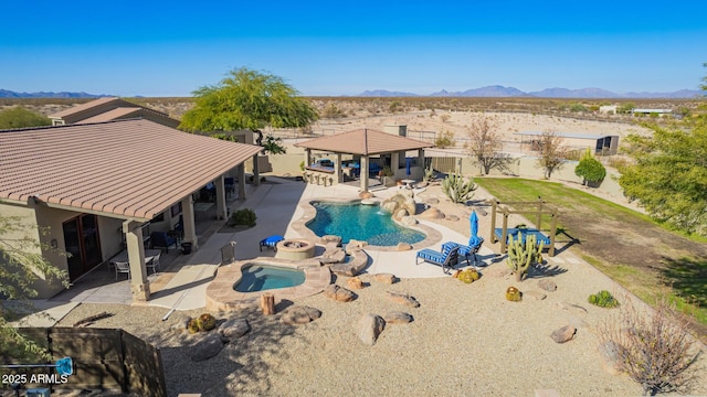 view of pool featuring a mountain view, a patio area, and an in ground hot tub