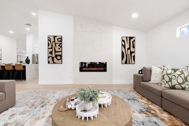 living area featuring a tiled fireplace, recessed lighting, wood finished floors, and visible vents