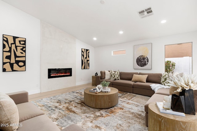 living area featuring visible vents, wood finished floors, recessed lighting, a large fireplace, and lofted ceiling