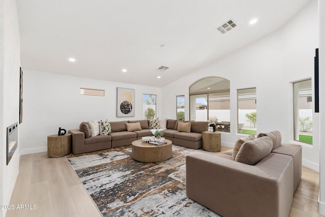 living room with recessed lighting, visible vents, light wood-style flooring, and arched walkways