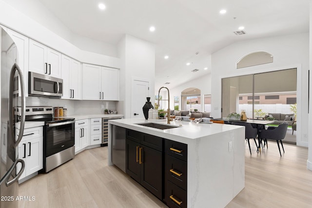 kitchen featuring white cabinetry, open floor plan, appliances with stainless steel finishes, and a sink