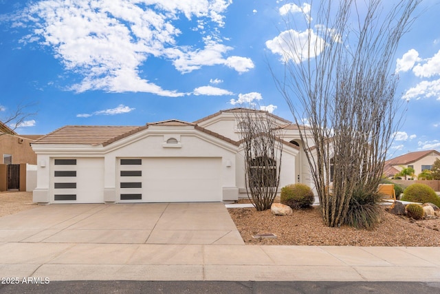 view of front of home with stucco siding, concrete driveway, an attached garage, and a tile roof