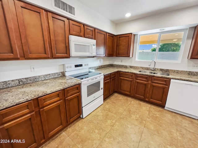 kitchen featuring light stone countertops, white appliances, and sink