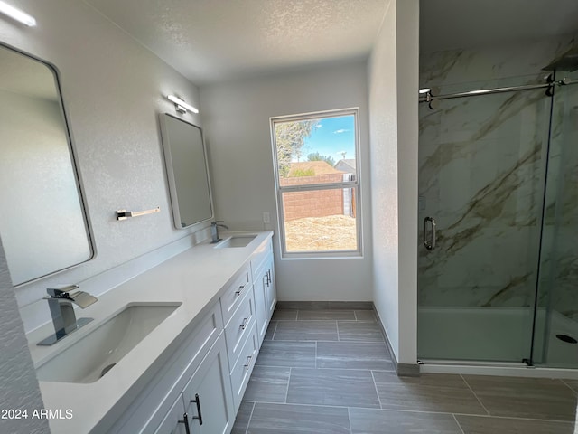 bathroom featuring a textured ceiling, an enclosed shower, and vanity