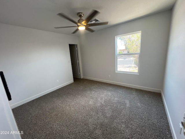 empty room featuring ceiling fan and dark carpet