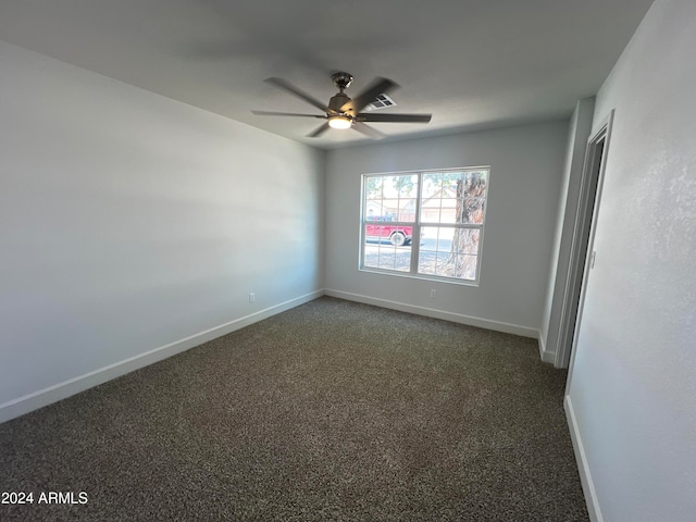 spare room with ceiling fan and dark carpet