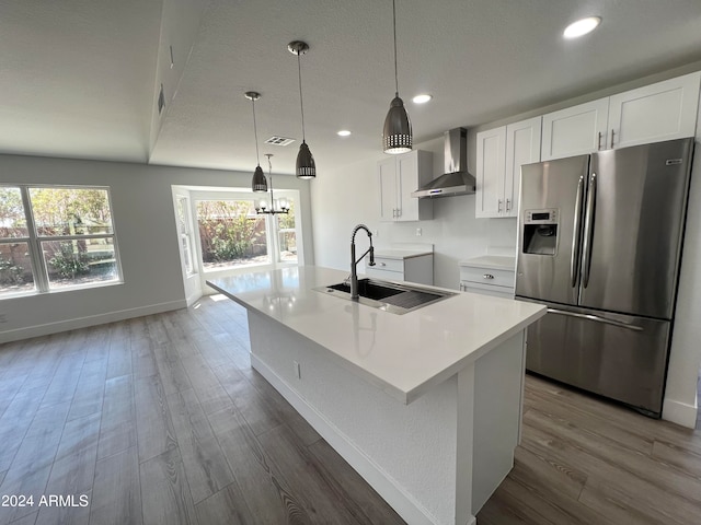 kitchen featuring wall chimney exhaust hood, sink, white cabinetry, and stainless steel fridge