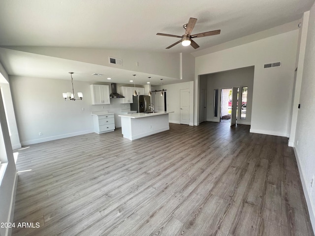 unfurnished living room with light wood-type flooring, ceiling fan with notable chandelier, high vaulted ceiling, and sink