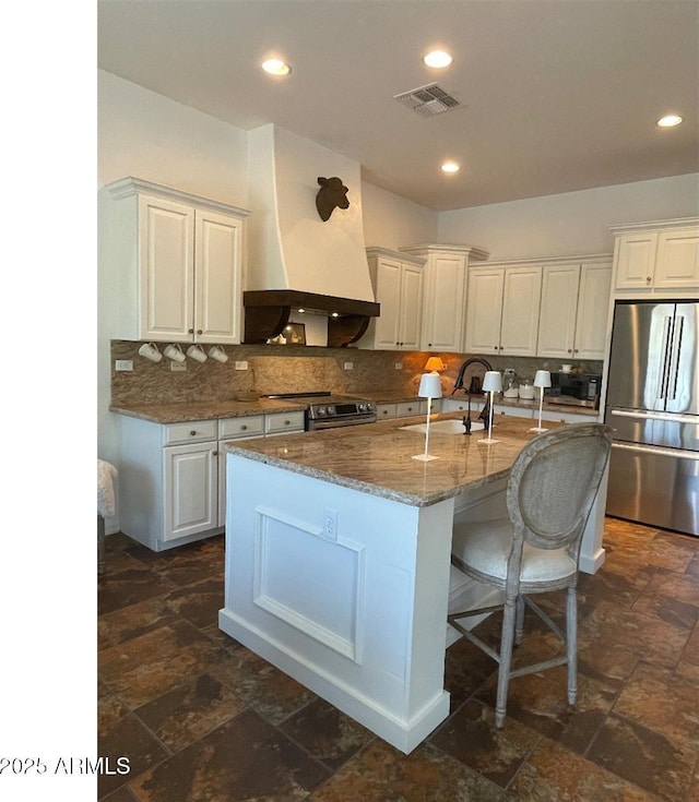 20502 W Ridge Rd, Buckeye, AZ 85396 - kitchen featuring appliances with stainless steel finishes, custom range hood, backsplash, white cabinetry, and stone counters