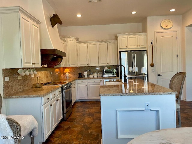 20502 W Ridge Rd, Buckeye, AZ 85396 - kitchen featuring appliances with stainless steel finishes, light stone counters, tasteful backsplash, an island with sink, and white cabinetry