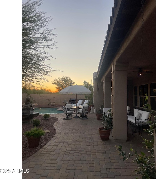 20502 W Ridge Rd, Buckeye, AZ 85396 - patio terrace at dusk with a patio area, a fenced backyard, outdoor dining area, and ceiling fan