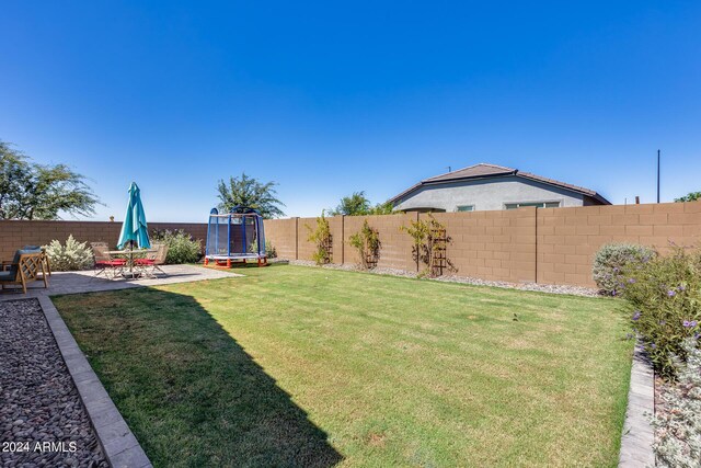 view of yard featuring a trampoline and a patio