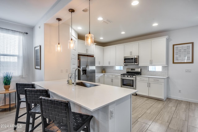 kitchen featuring a breakfast bar, stainless steel appliances, white cabinets, and pendant lighting