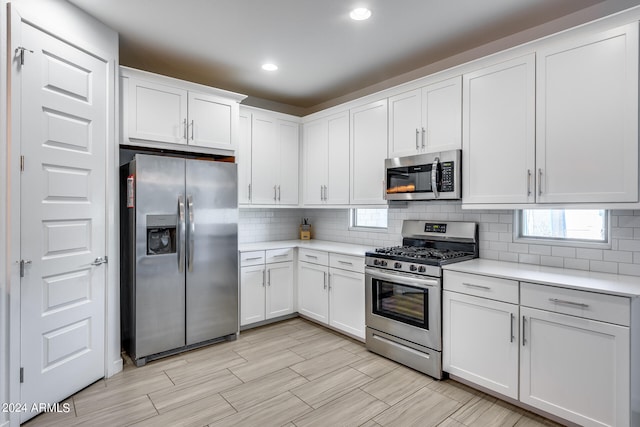 kitchen featuring decorative backsplash, white cabinetry, and appliances with stainless steel finishes