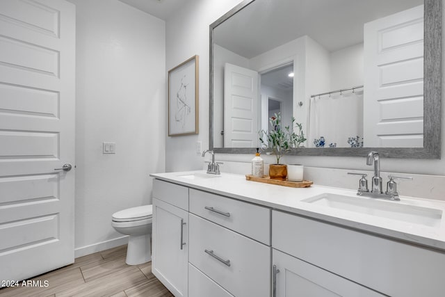 bathroom with wood-type flooring, vanity, and toilet