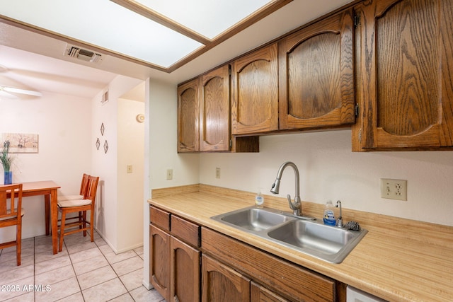 3131 W Cochise Dr Unit 144, Phoenix, AZ 85051 - kitchen featuring a sink, light countertops, light tile patterned floors, brown cabinets, and a ceiling fan