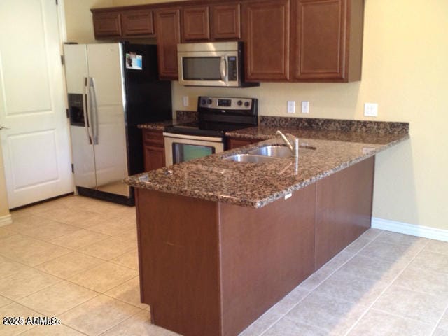 kitchen with kitchen peninsula, dark stone countertops, sink, and stainless steel appliances