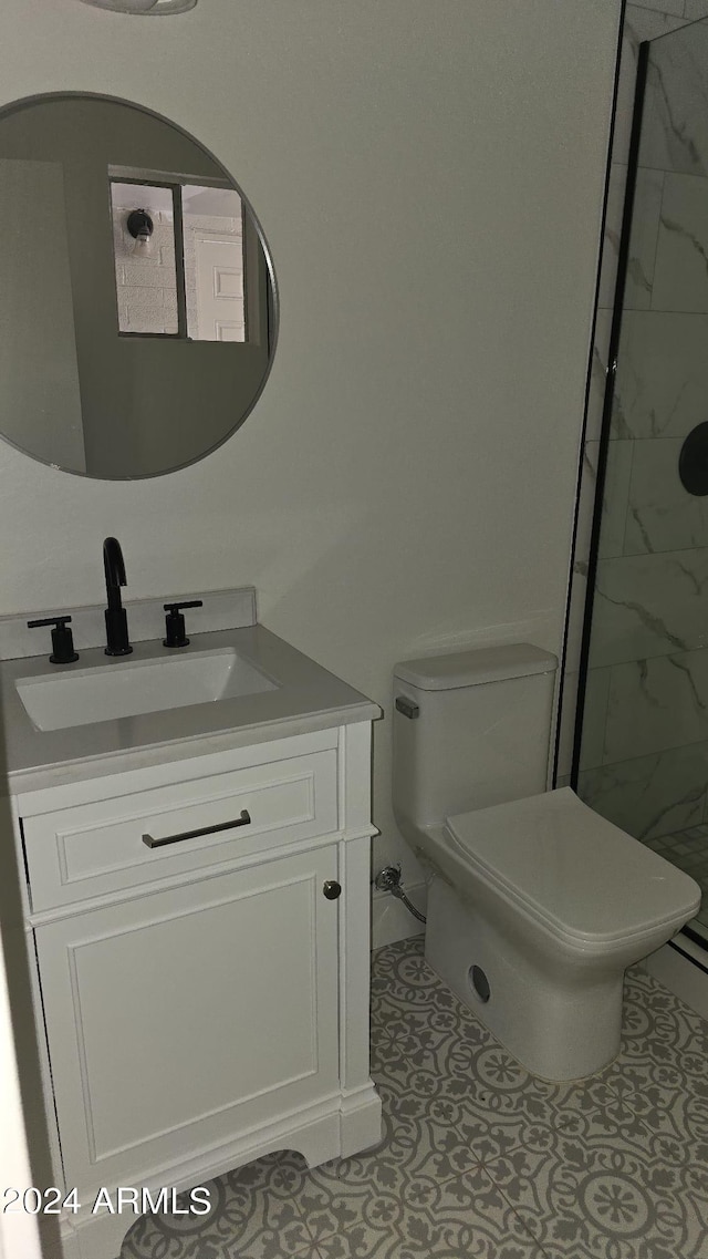 bathroom with vanity, toilet, a tile shower, and tile patterned flooring