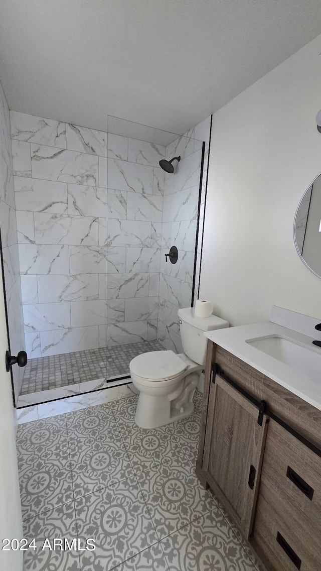 bathroom featuring vanity, toilet, tile patterned floors, and tiled shower