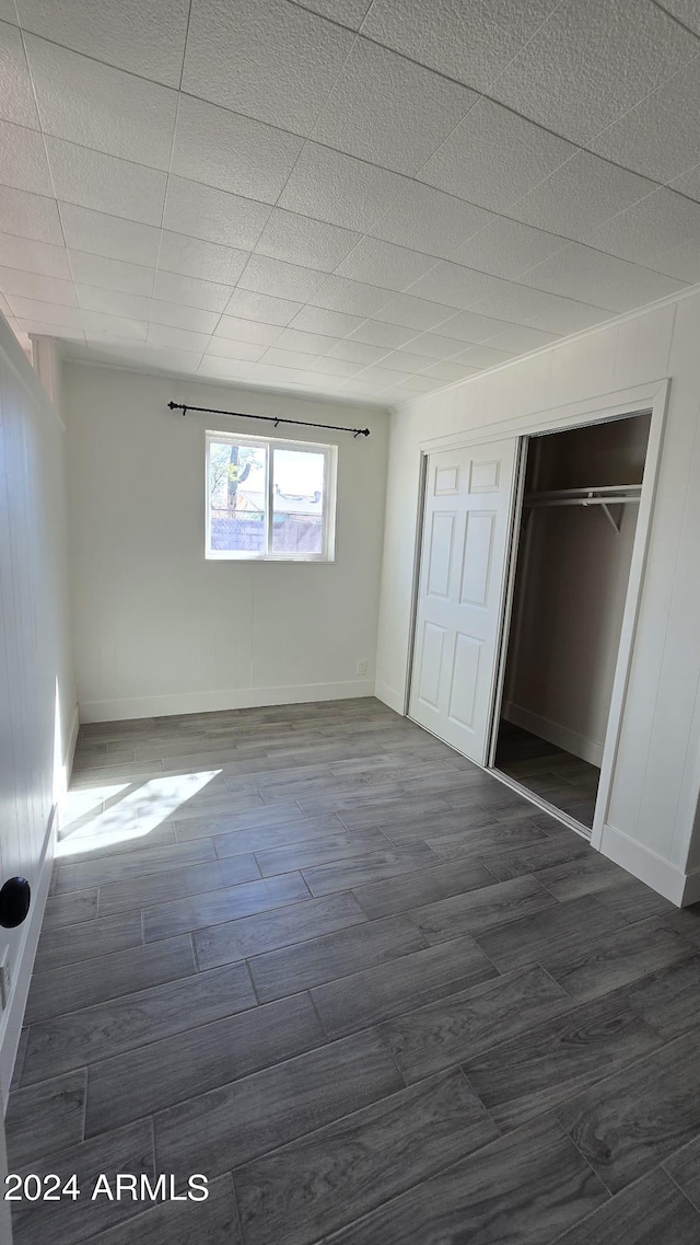 unfurnished bedroom with dark hardwood / wood-style floors and a closet