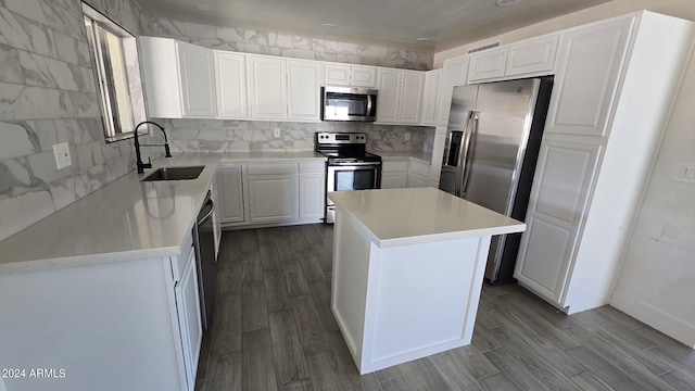 kitchen featuring appliances with stainless steel finishes, sink, a center island, white cabinetry, and light hardwood / wood-style floors