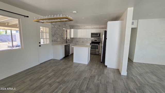 kitchen featuring appliances with stainless steel finishes, white cabinetry, wood-type flooring, sink, and a center island