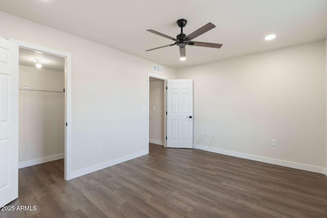 unfurnished bedroom with ceiling fan, a spacious closet, dark hardwood / wood-style floors, and a closet