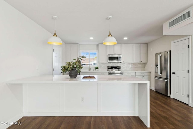 kitchen with white cabinetry, appliances with stainless steel finishes, hanging light fixtures, and backsplash