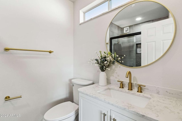 bathroom with vanity, toilet, and a shower with door