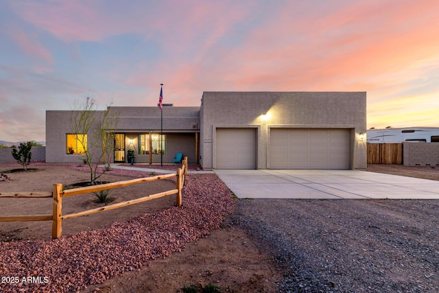 view of front of house featuring concrete driveway, stucco siding, fence, and an attached garage